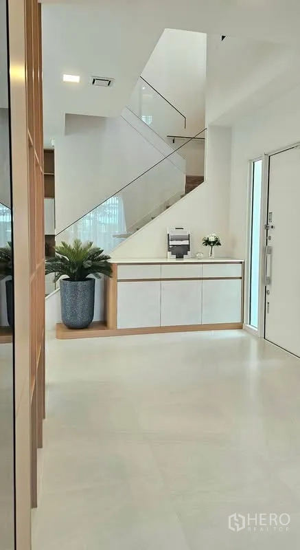 บ้านเดี่ยว for rent in Bang Phli, Samut Prakan - โถงทางเข้าพร้อมบันไดราวกระจกและตู้คอนโซลสีขาว.
