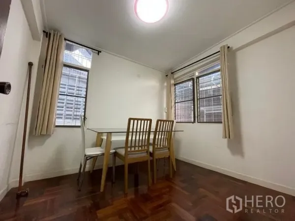 Detached House for rent in Khlong Toei, Bangkok - Cozy dining nook with glass-top table, four chairs and corner windows.