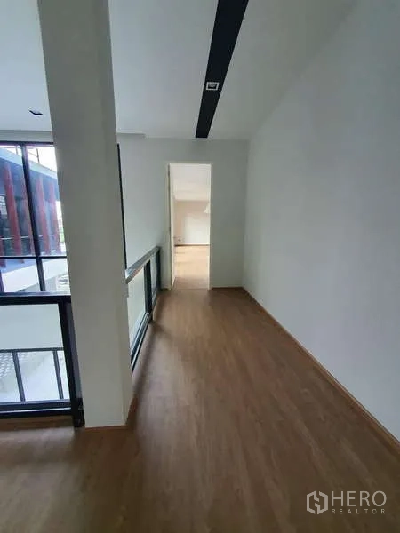 独立式住宅 出租在Phra Khanong, Bangkok - 楼上走廊，木地板与玻璃栏杆，面向内庭。