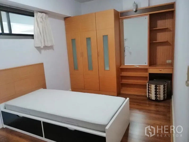 Condominium for rent in Watthana, Bangkok - Bedroom with single bed, built-in wooden wardrobe, and dressing desk.