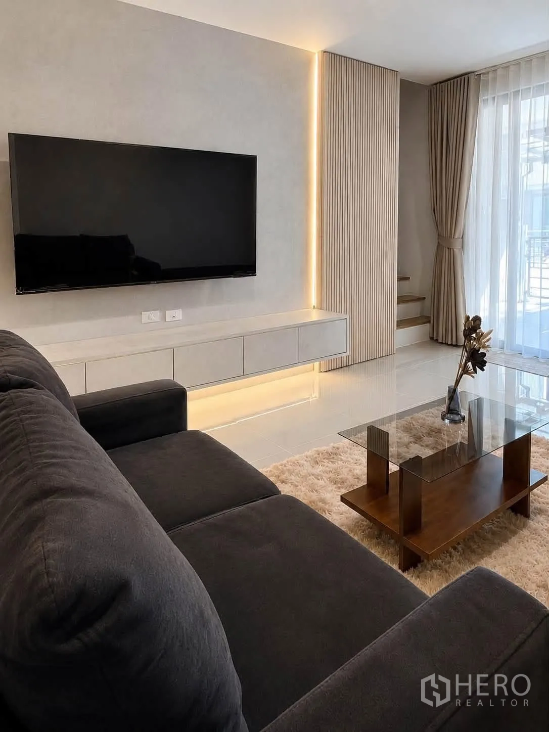 Townhouse for rent in Bang Phli, Samut Prakan - Lounge area with a wall-mounted TV, floating cabinet, and LED accent lighting.