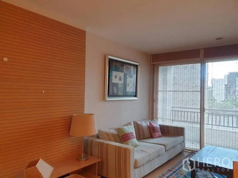 คอนโด ให้เช่าในWatthana, Bangkok - ห้องนั่งเล่นอบอุ่น โซฟาลายริ้ว หน้าต่างเต็มบาน และระเบียงเห็นวิวเมือง