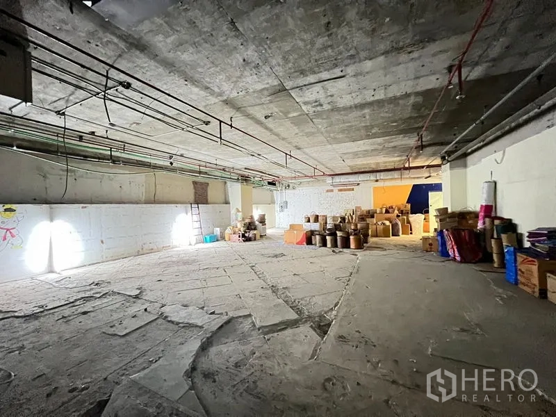 零售空间 出租 - 开放式零售壳体，粗糙混凝土地面，墙面灯光与打包箱。