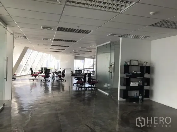 办公空间 出租在Khlong Toei, Bangkok - 宽敞办公空间，玻璃隔断、吊顶灯光与抛光水泥地面，配有转椅与书架。