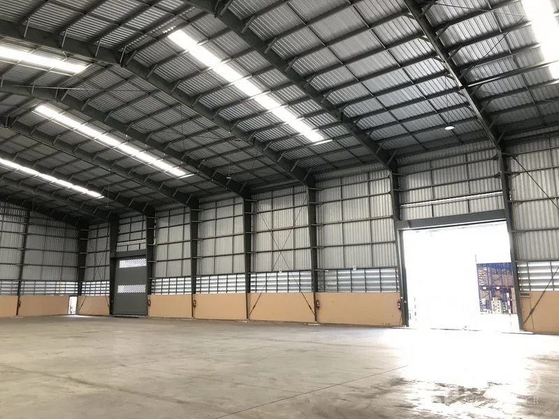 Warehouse for rent in Pathum Thani - Warehouse interior showing roller shutter entrance, ventilated walls and expansive loading space.