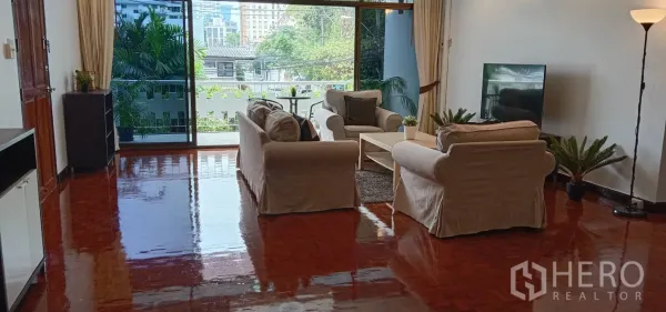 อพาร์ทเมนท์ ให้เช่าในRatchathewi, Bangkok - โถงรับแขกเชื่อมระเบียงด้วยประตูกระจกบานเลื่อน มองวิวต้นไม้และเมือง