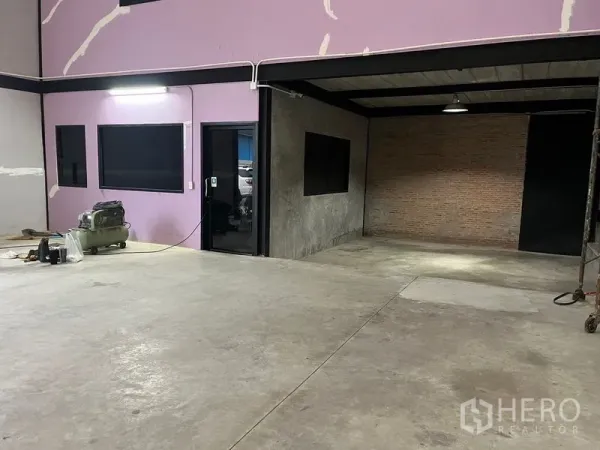 Warehouse for rent in Lat Krabang, Bangkok - Warehouse interior with polished concrete floor, internal office with glass door, and brick accent wall under industrial lighting.