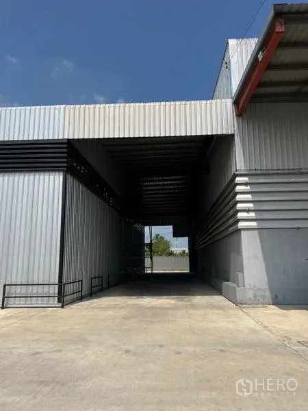Warehouse for rent in Pathum Thani - Drive-through covered bay connecting warehouse sections with metal cladding.