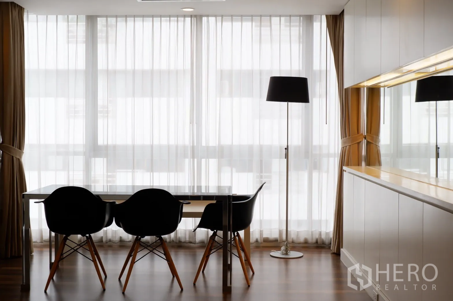 คอนโด ให้เช่าในPathum Wan, Bangkok - มุมรับประทานอาหารสว่างโปร่ง โต๊ะกระจก เก้าอี้สีดำ หน้าต่างสูงจรดเพดาน และโคมไฟตั้งพื้น