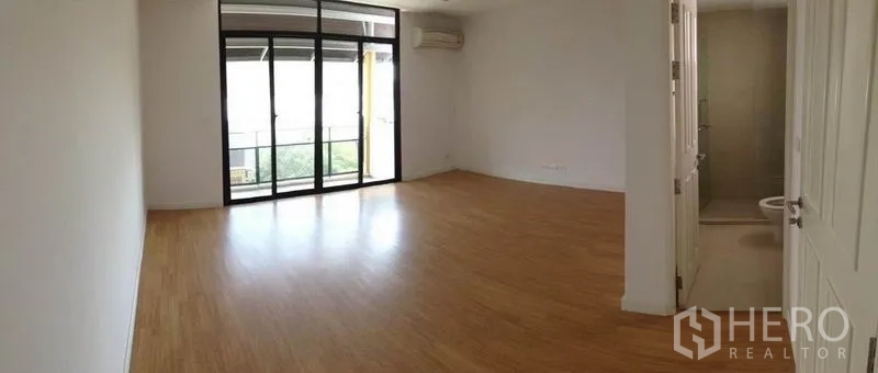 Townhouse for rent in Yan Nawa, Bangkok - Wide bedroom opening to a balcony through sliding doors; wood flooring throughout.