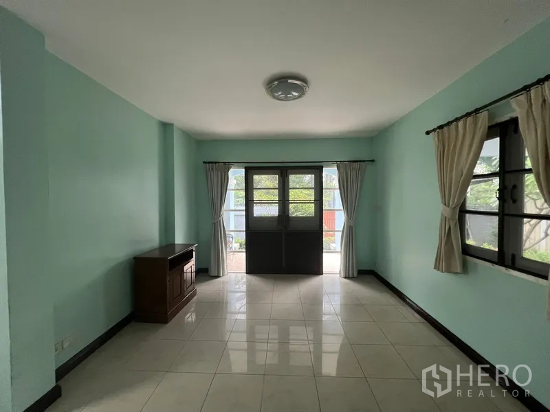 Detached House for rent in Bang Na, Bangkok - Living room opening to the patio through double doors with curtains