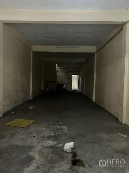 店屋 出租在Watthana, Bangkok - 店屋一层空旷大厅，水泥地与米色墙面，后方设楼梯，适合翻新改造。