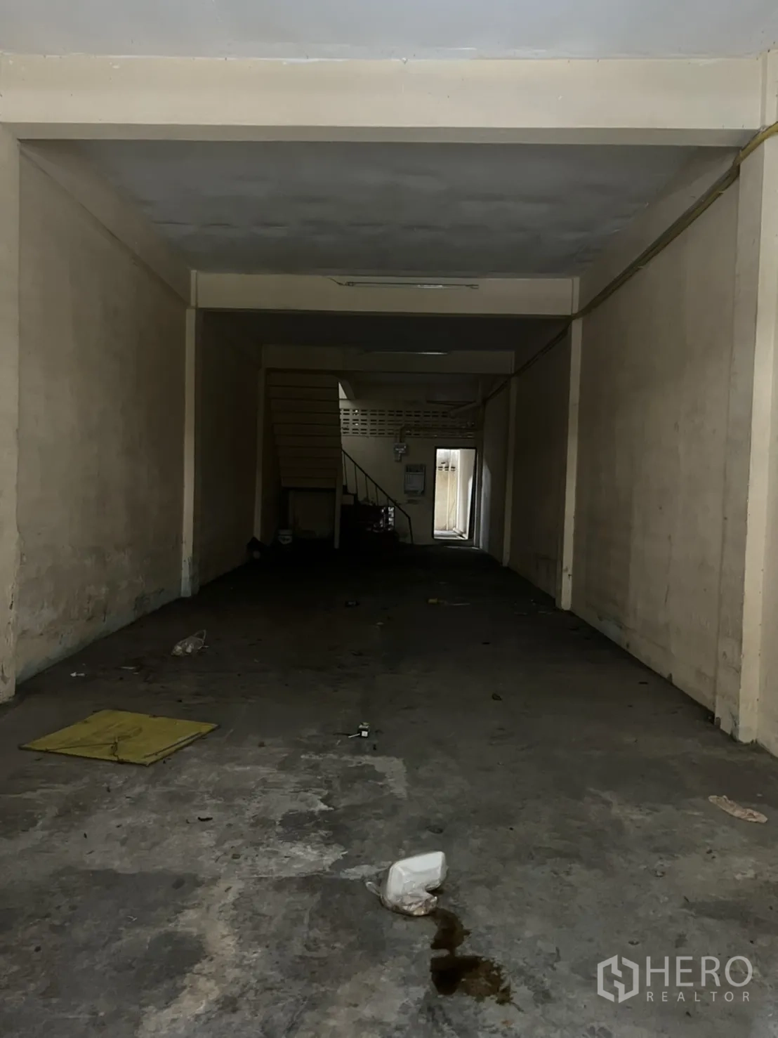 店屋 出租在Watthana, Bangkok - 店屋一层空旷大厅，水泥地与米色墙面，后方设楼梯，适合翻新改造。