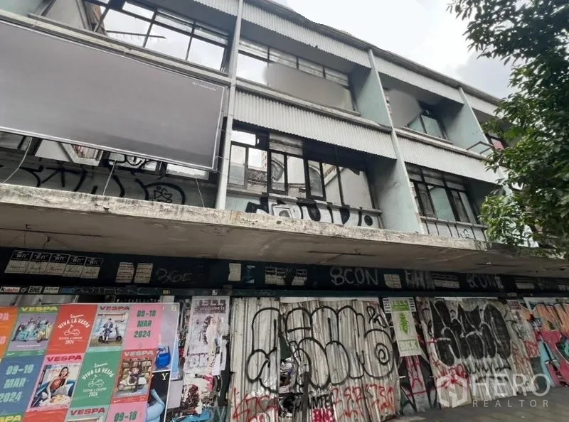 ที่ดิน ให้เช่าในWatthana, Bangkok - ตึกเตี้ยติดถนนด้านหน้า มีประตูม้วนปิดและกราฟฟิตีย่านเอกมัย