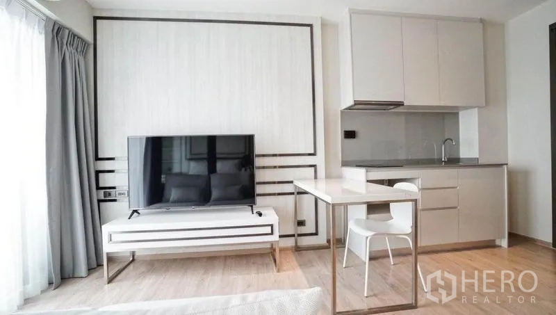 公寓 出售在Khlong Toei, Bangkok - 极简小厨房，顶柜、灶台、水槽，以及带平板电视的电视柜。