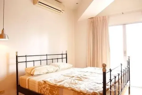 Condominium for rent in Ratchathewi, Bangkok - Airy bedroom with metal bedframe, white walls, air conditioner and balcony doors.