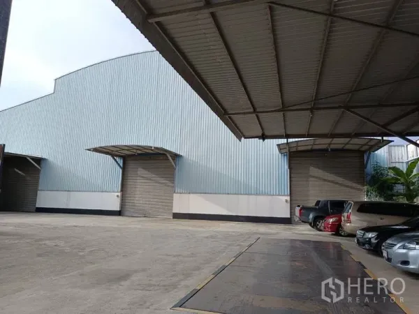 工厂 出售在Ban Phaeo, Samut Sakhon - 金属板外墙的工厂外观，带有遮雨装卸棚、卷闸门与停车区