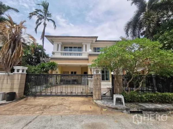独立式住宅 出租 - 两层独栋别墅外立面，带大门车道、阳台与成熟热带树木。