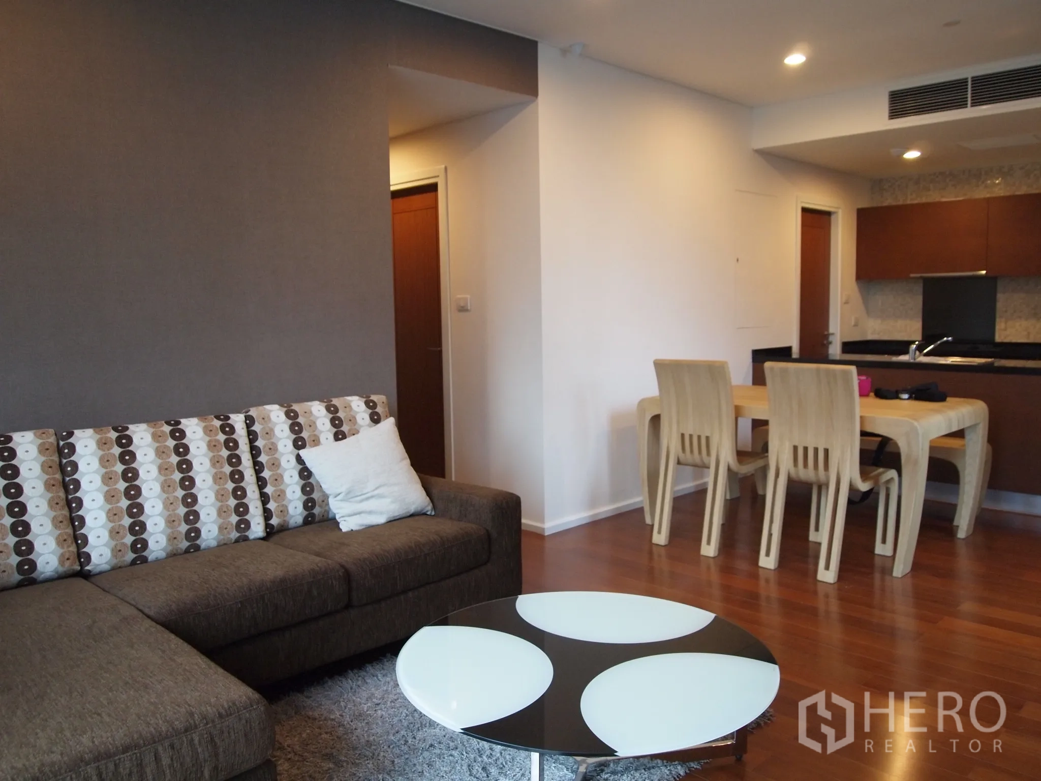 คอนโด ให้เช่าหรือขายในWatthana, Bangkok - พื้นที่นั่งเล่นแบบโอเพ่นแพลน โซฟา L‑shape ชุดทานข้าว และครัวด้านหลัง