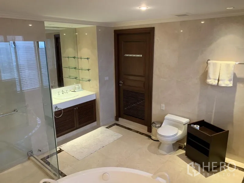 Condominium for rent or sale in Watthana, Bangkok - Marble bathroom with glass shower, soaking tub edge, vanity and toilet.
