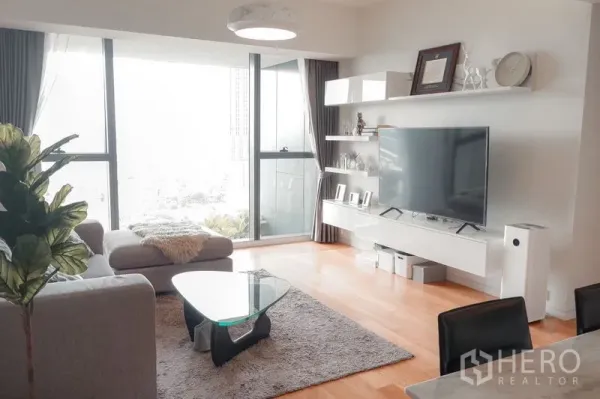 公寓 出租在Sathon, Bangkok - 采光充足的起居室，转角沙发、玻璃茶几并连通阳台