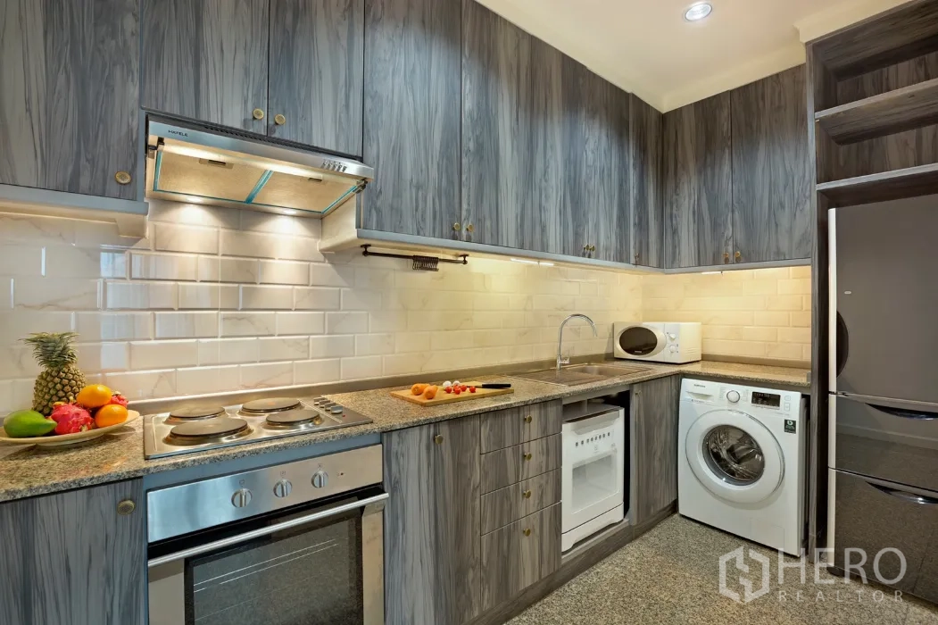 Condominium for rent in Khlong San, Bangkok - Modern U-shaped kitchen with oven, cooktop, washing machine, gray cabinets and subway tile backsplash.
