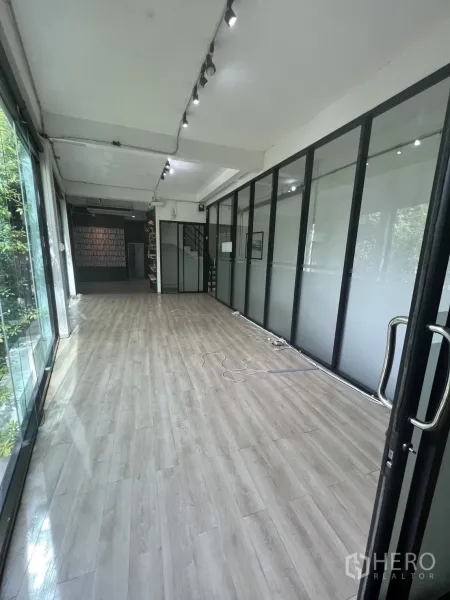 零售空间 出租在Watthana, Bangkok - 开放式零售楼层，浅色木地板，玻璃隔间与轨道灯。