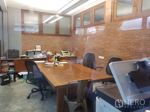 Home Office for rent in Watthana, Bangkok - Glass-enclosed meeting room with brick walls and a large wooden table.