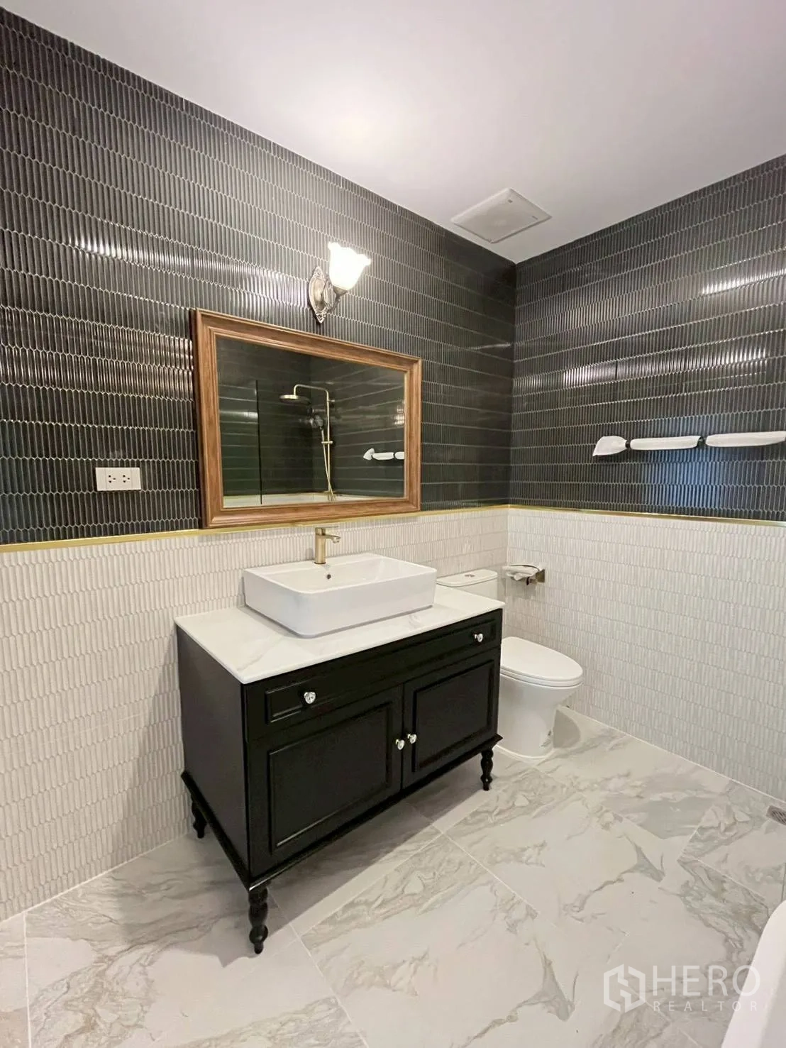 ทาวน์เฮาส์ for rent in Khlong Toei, Bangkok - ห้องน้ำพร้อมตู้ล้างหน้า โถสุขภัณฑ์ และผนังไทล์สีเข้ม.