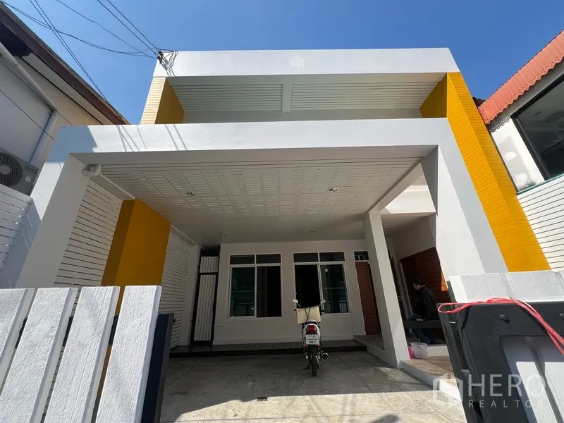 Townhouse for rent in Din Daeng, Bangkok - Modern two-storey townhouse exterior with white frame, yellow accents and a covered carport.