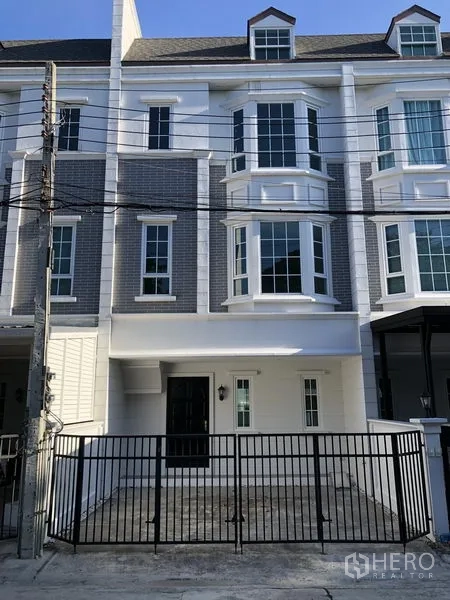 Townhouse for rent in Bang Kapi, Bangkok - Three-storey townhouse exterior with bay windows and a gated carport in Bang Kapi, Bangkok.
