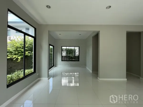 Detached House for sale in Suan Luang, Bangkok - Dining nook beside floor-to-ceiling windows overlooking green hedges.