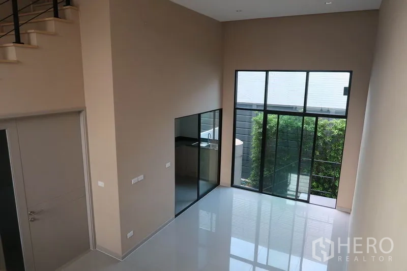 ทาวน์เฮาส์ ให้เช่าในSuan Luang, Bangkok - ห้องรับแขกสว่างพร้อมผนังกระจกเปิดสู่สวนเล็ก และครัวกั้นกระจก