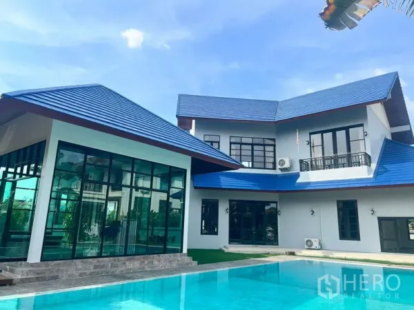 Detached House for sale in Prawet, Bangkok - Contemporary house façade with blue rooflines reflected in the pool water.