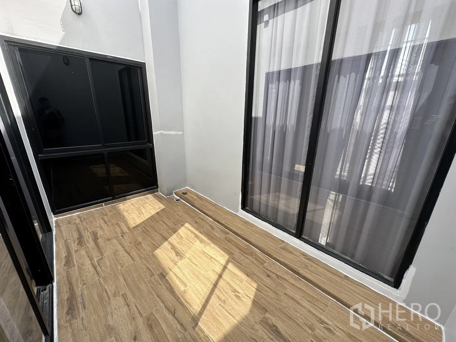 带办公室的家 出租或出售在Suan Luang, Bangkok - 紧凑的采光天井露台，木纹地砖与黑框玻璃门。