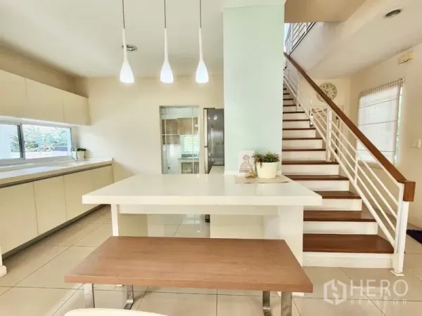 独立式住宅 出租在Prawet, Bangkok - 开放式餐区与岛台，吊灯和楼梯相连，通向厨房。