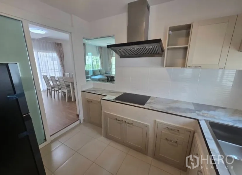 Detached House for rent in Bang Phli, Samut Prakan - Closed kitchen with induction hob, range hood, marble‑look counters and tiled backsplash.
