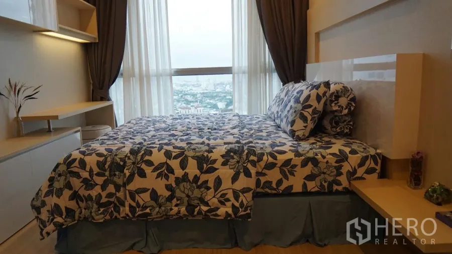 คอนโด ให้เช่าในWatthana, Bangkok - ห้องนอนอบอุ่นพร้อมหน้าต่างเต็มผนัง วิวเมือง ผ้าปูดอกไม้ และโต๊ะกับชั้นวางบิวท์อิน