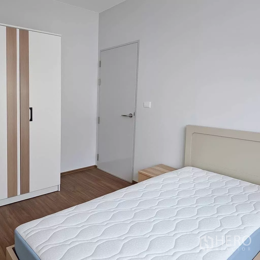 ทาวน์เฮาส์ ให้เช่าในBang Phli, Samut Prakan - ห้องนอนที่สองมีตู้เสื้อผ้า โต๊ะหัวเตียง และที่นอน พื้นไม้.