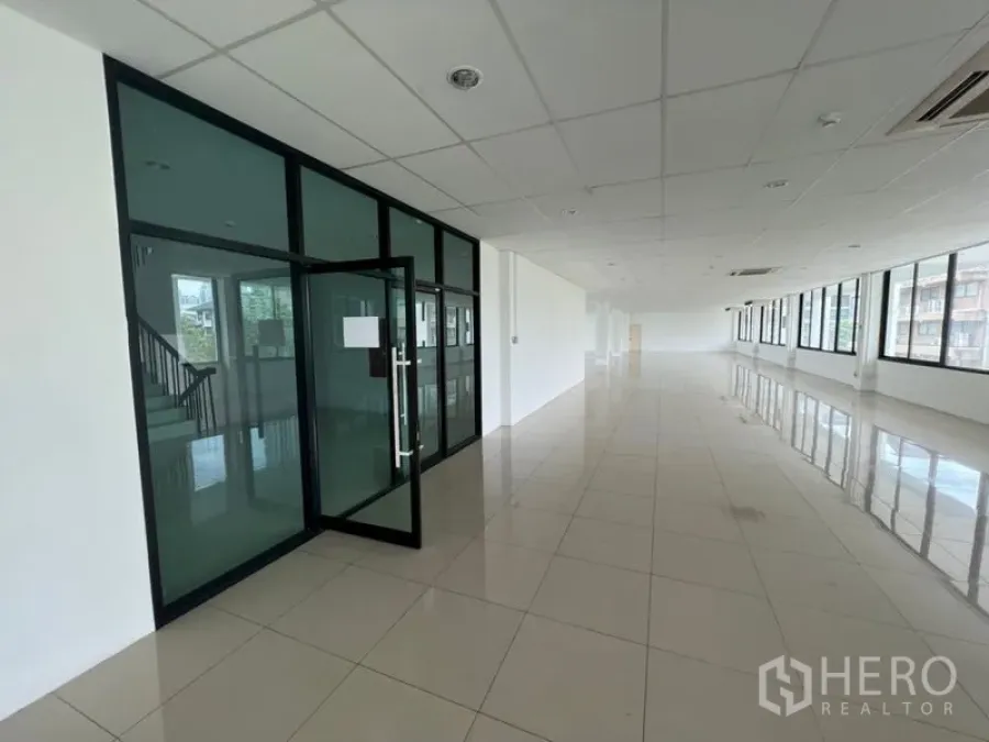 สำนักงาน ให้เช่า - พื้นที่สำนักงานแบบเปิดโล่ง พร้อมประตูกระจกกั้นพื้นกระเบื้อง ฝ้าเพดาน และหน้าต่างยาวในย่านพระโขนง กรุงเทพฯ