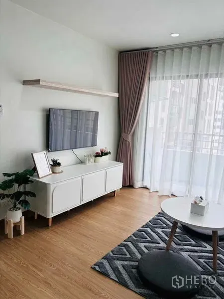 Condominium for rent in Watthana, Bangkok - TV wall with white console and balcony windows bringing natural light.