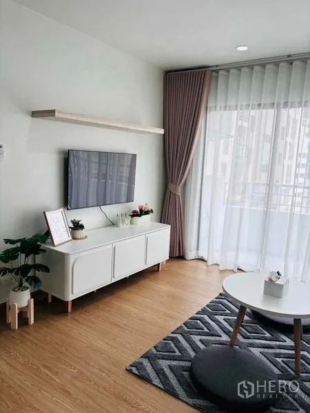 Condominium for rent in Watthana, Bangkok - TV wall with white console and balcony windows bringing natural light.