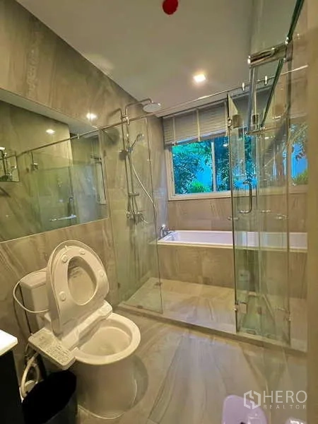 Condominium for sale in Watthana, Bangkok - Master bathroom with separate glass shower and bathtub in gray stone tile.