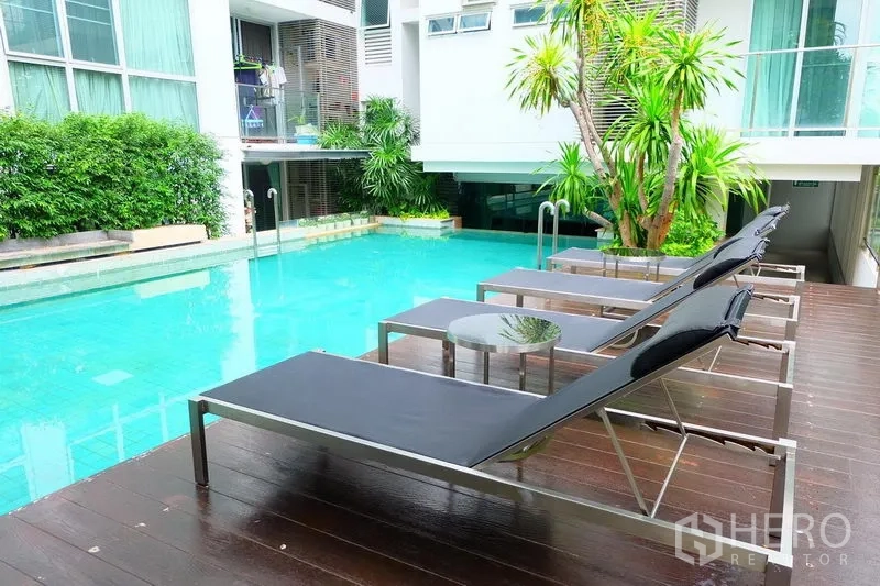 คอนโด ให้เช่าในPhaya Thai, Bangkok - สระว่ายน้ำกลางแจ้งพร้อมเตียงอาบแดด พื้นไม้ และต้นไม้ทรอปิคัล