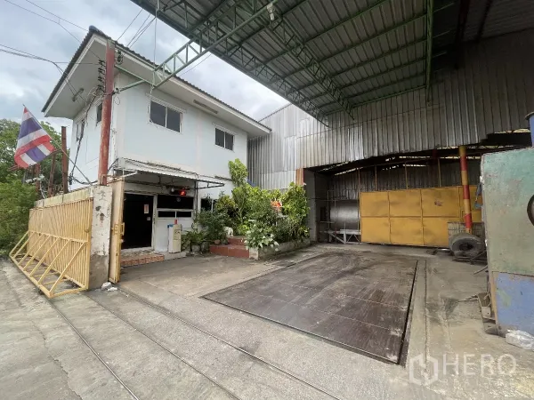 工厂 出售在Bang Bua Thong, Nonthaburi - 工厂入口，带两层办公楼、雨棚和大型地磅称重平台。