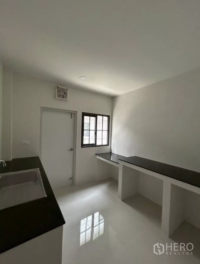 独立式住宅 出租在Bang Phli, Samut Prakan - 独立厨房，黑色台面、洗槽、窗户与后门。