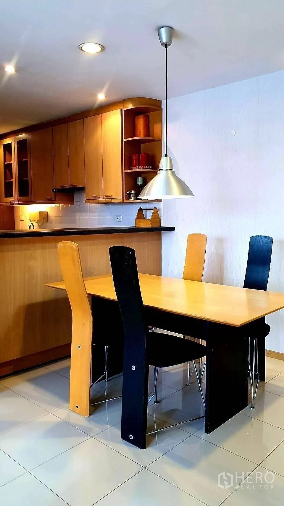 Condominium for rent in Khlong Toei, Bangkok - Dining area close-up with pendant light over a wooden table and modern chairs.