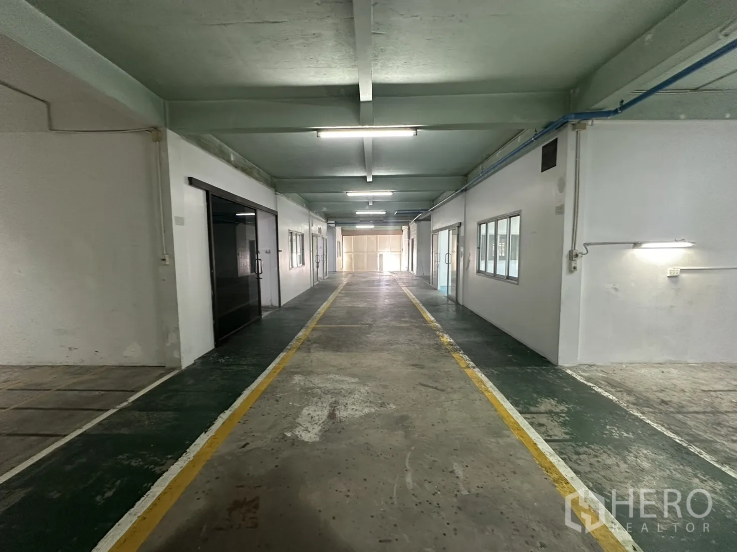 Warehouse for rent in Bang Na, Bangkok - Long internal corridor with marked lanes, windows and overhead piping.