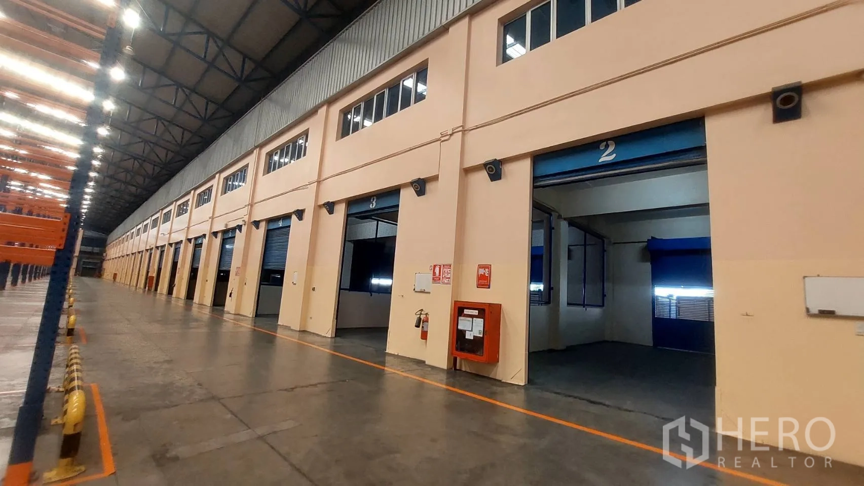 货栈 出租在Mueang Pathum Thani, Pathum Thani - 一排装卸月台，配卷帘门、消防设备与货架。