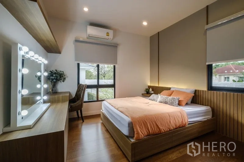 Detached House for rent in Phasi Charoen, Bangkok - Cozy second bedroom with vanity mirror lights, wood accents and corner windows.